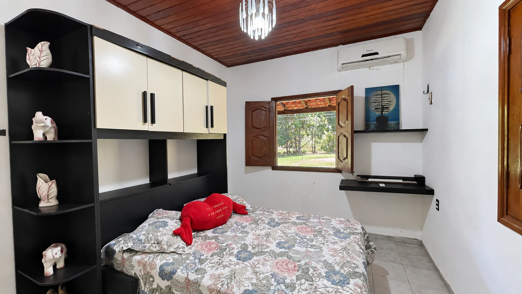 Quarto da casa com cama de casal, armários e janela voltada para o verde