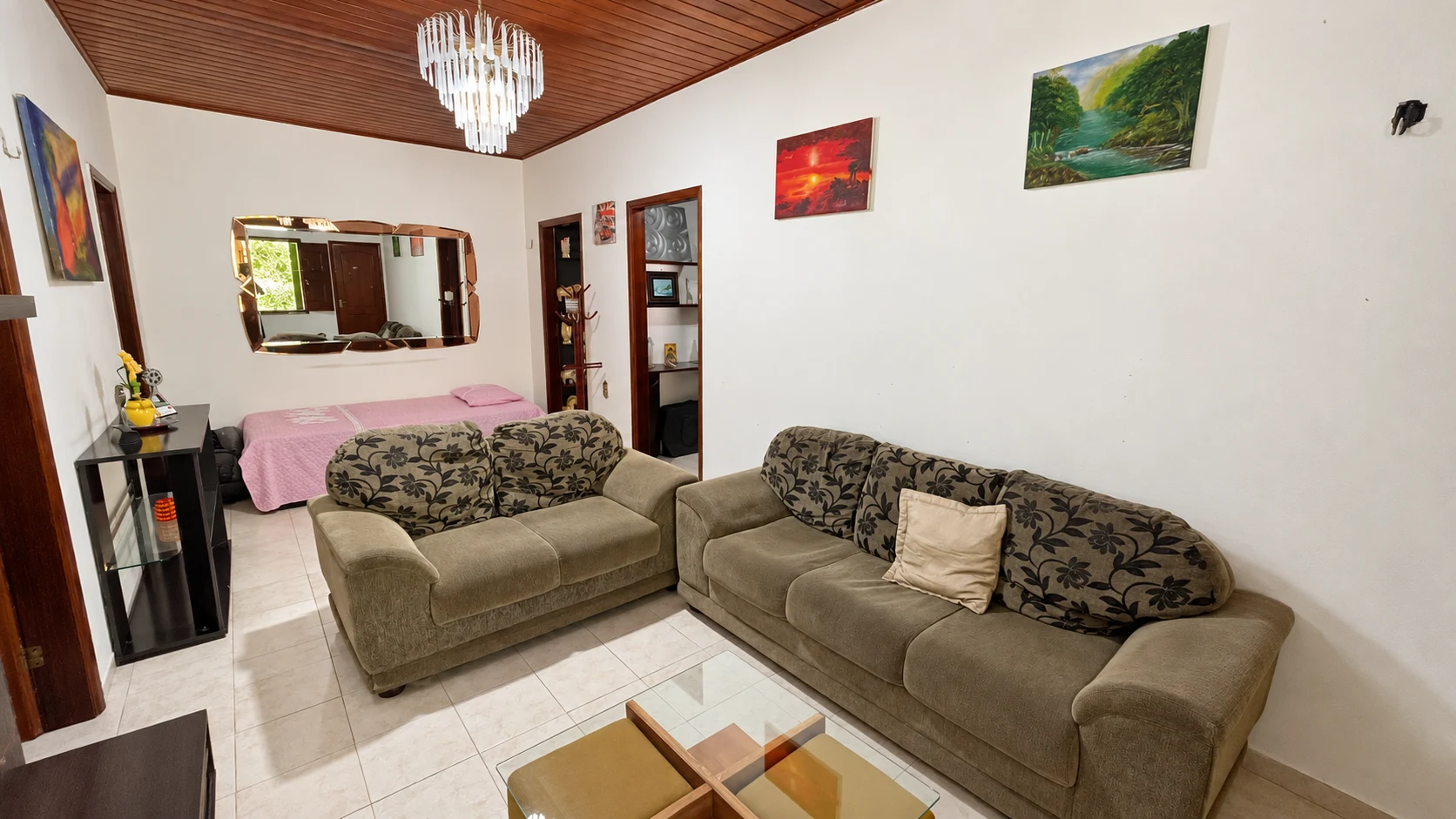 Sala de estar da casa com sofás, mesa de centro e cama de apoio