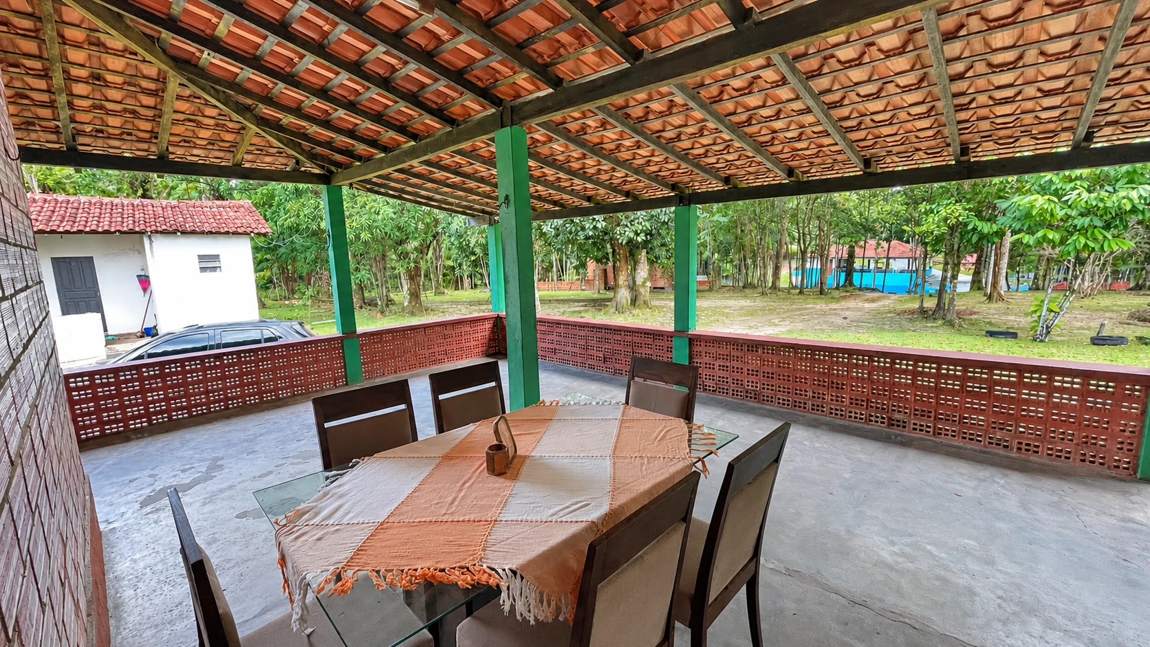 Varanda ampla e coberta com mesa e vista para a área verde